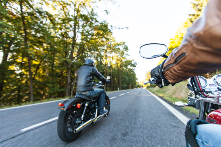 2 men riding motorcycles on a forest road