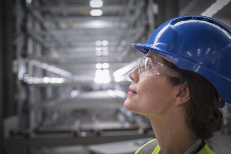 Female factory worker wearing safety googles and helmet