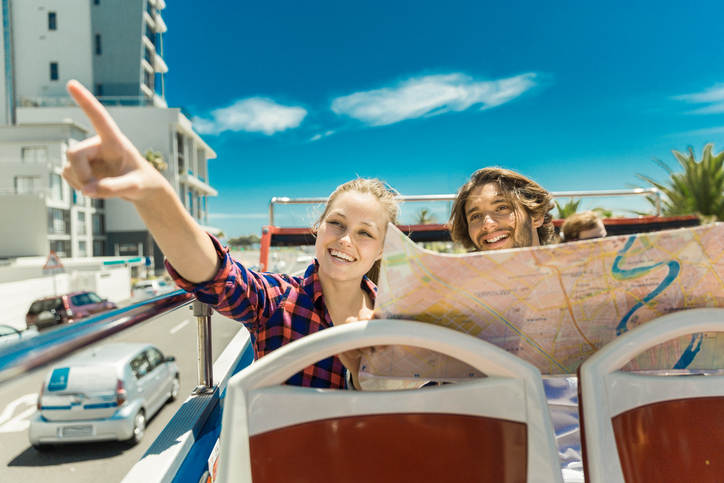 A woman and a man on a tour bus pointing out different sites.