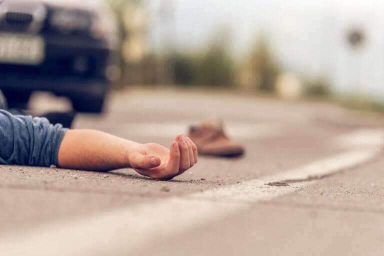 Car hit scene, male person lying on the floor in front of a car