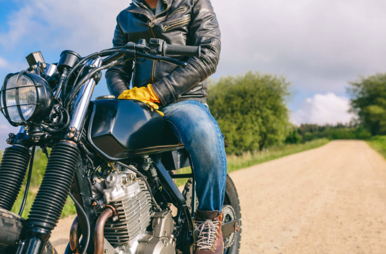 Man about to ride a motorcycle on dirt road.