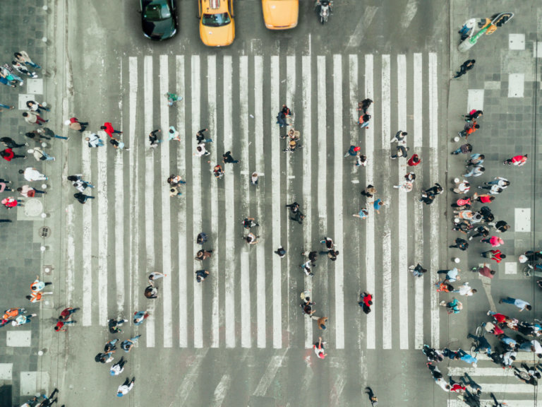 Pedestrians walking in traffic at a designated crosswalk.