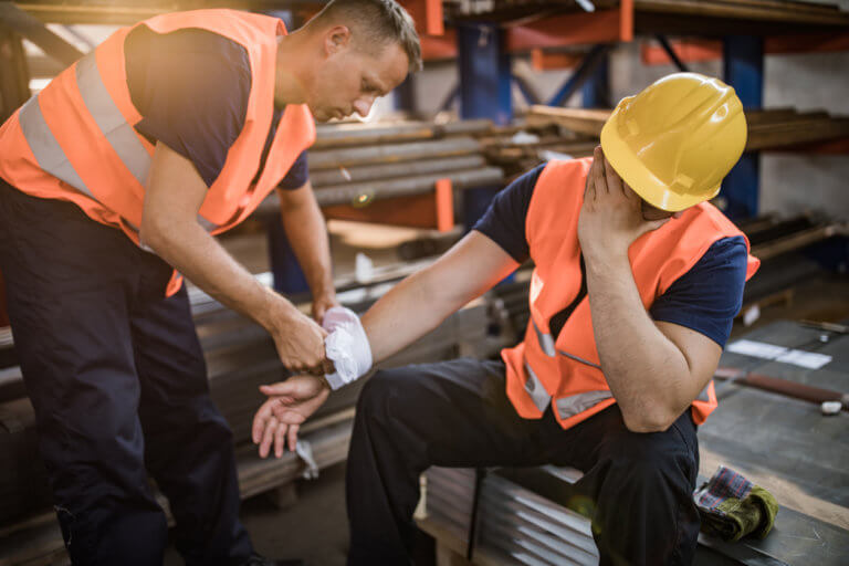 Man who was injured in a construction accident being helped by worker.