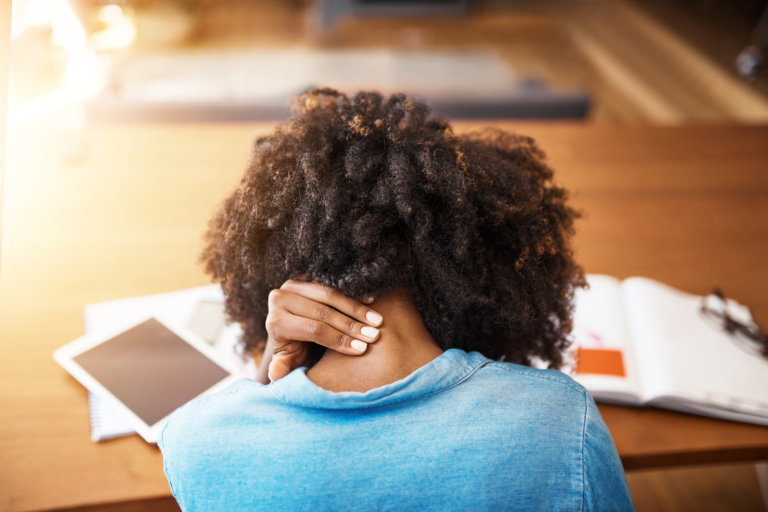 Woman touching her neck injury while worried about her taxes and personal injury settlement.