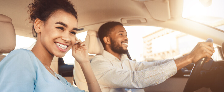 man smiling and driving with a female passenger smiling whiplash from a car accident