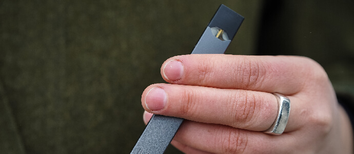 A woman is holding a Juul e-cigarette, juul burn injury