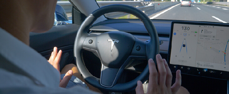 man driving a tesla with no hands on the steering wheel