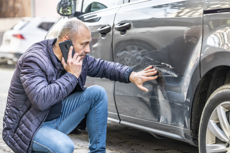 man checking damage on car