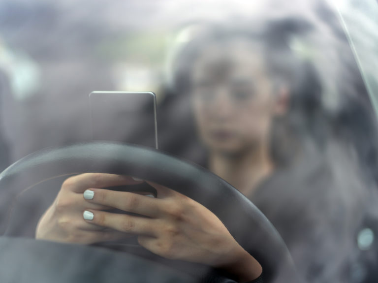 Teen driver distracted by her cell phone.