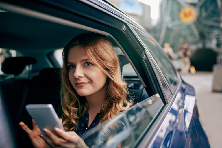 Shot of an attractive young woman using a mobile phone while traveling in a car