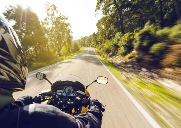 Motorcycle speeding down on an empty country road from over rider"u2019s point of view. Focus is on the motorbike with road motion blurred