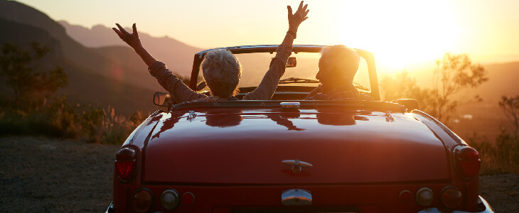 older man and woman with hands in the air in a red convertible on a cliff reckless driving accident