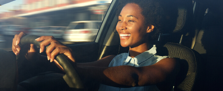 woman driving with a big smile on her face uninsured motorist