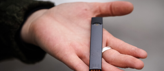 A woman is holding a Juul e-cigarette, juul battery explosion