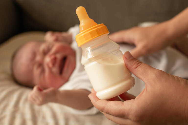 A parent trying to confort and feed a crying screaming baby over the milk formula