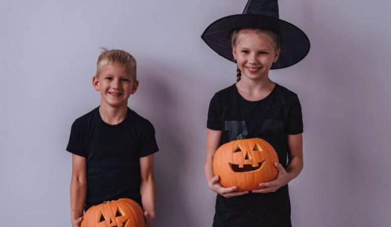 two kids in halloween costumes holding carved pumpkins in los angeles