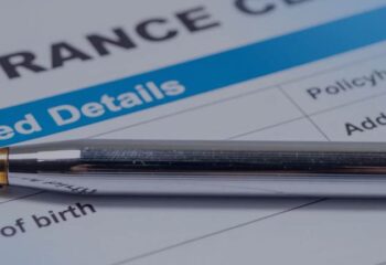 a pen laying atop a car insurance paper form
