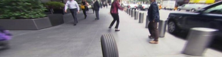 runaway tire on a sidewalk with people running in fear