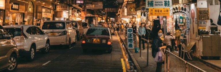 a busy street in Asia filled with cars and people at night time