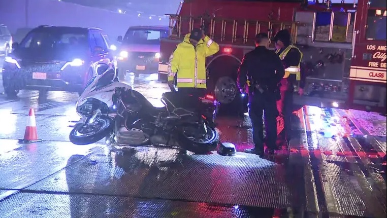 a photo of a crashed motorcycle on a california highway with firefighters and police all around