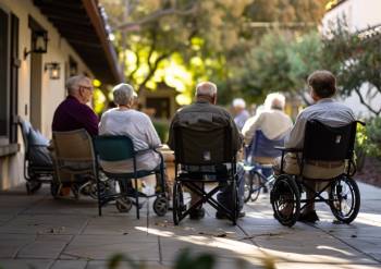 seniors sitting in chairs and wheelchairs outside of a nursing home in california